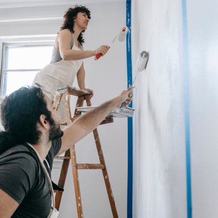 Paint & SuppliesA couple painting an interior wall with paint rollers.